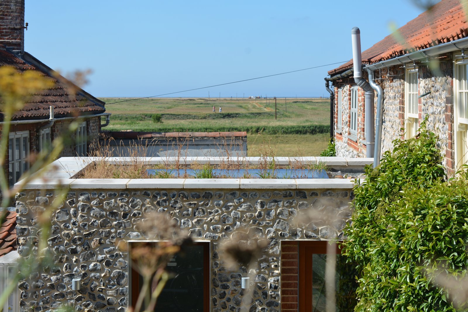 Coastal building project showing flintwork, rooflines, and surrounding landscape